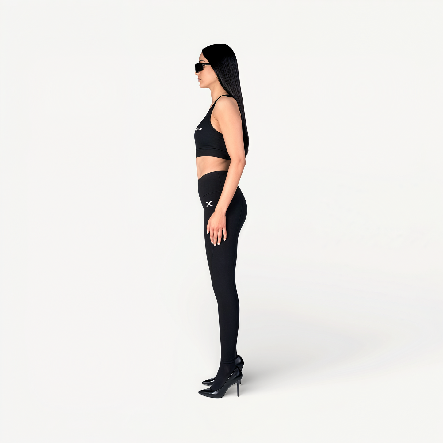 Woman wearing a black athletic outfit with ‘Elite’ ENVOLE logo on a white background.
