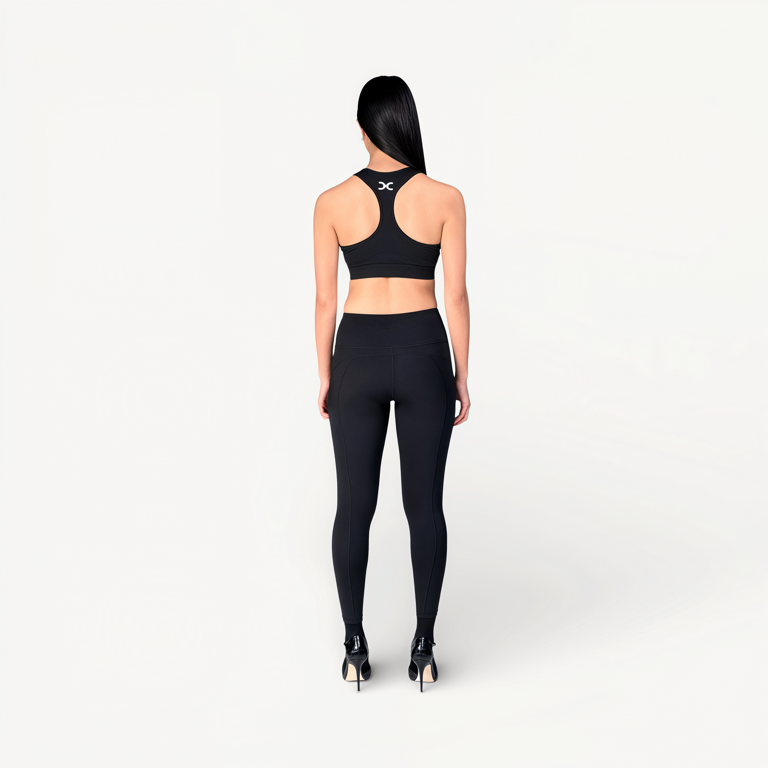 Woman wearing a black sports bra and leggings set with ‘Elite’ ENVOLE on a white background.