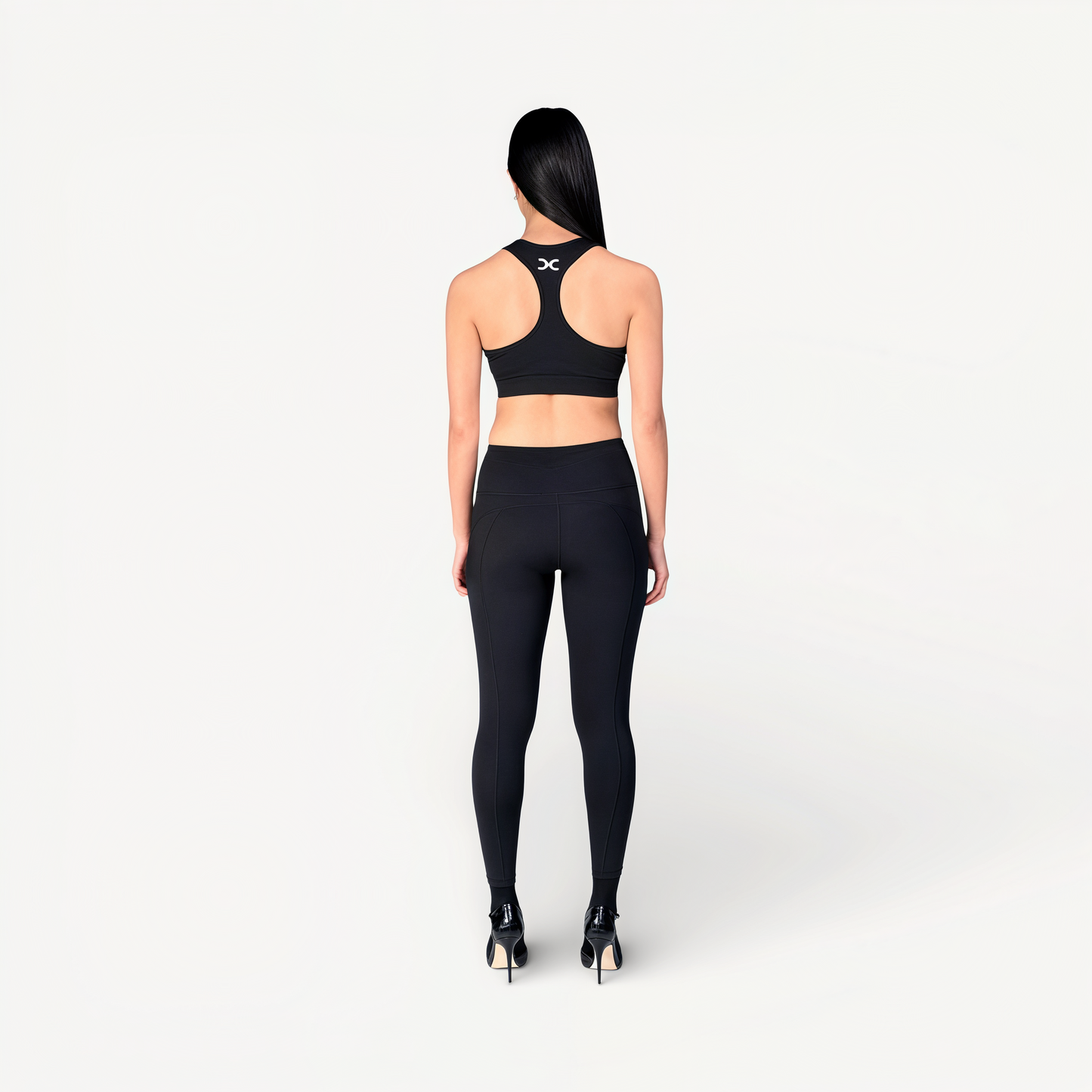 Woman wearing a black sports bra and leggings set with ‘Elite’ ENVOLE on a white background.