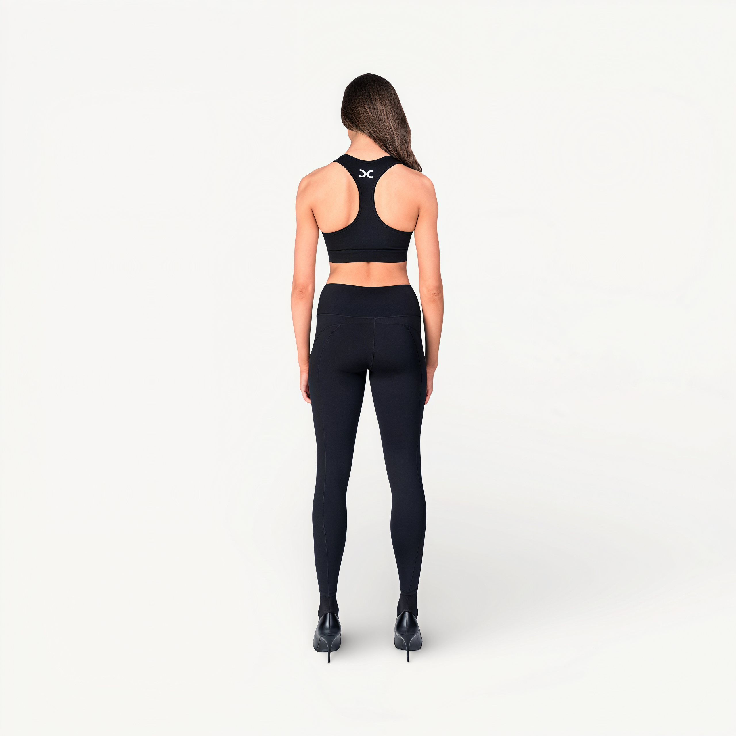 Woman wearing black athletic leggings and sports bra with ‘Elite’ ENVOLE on a white background back view.