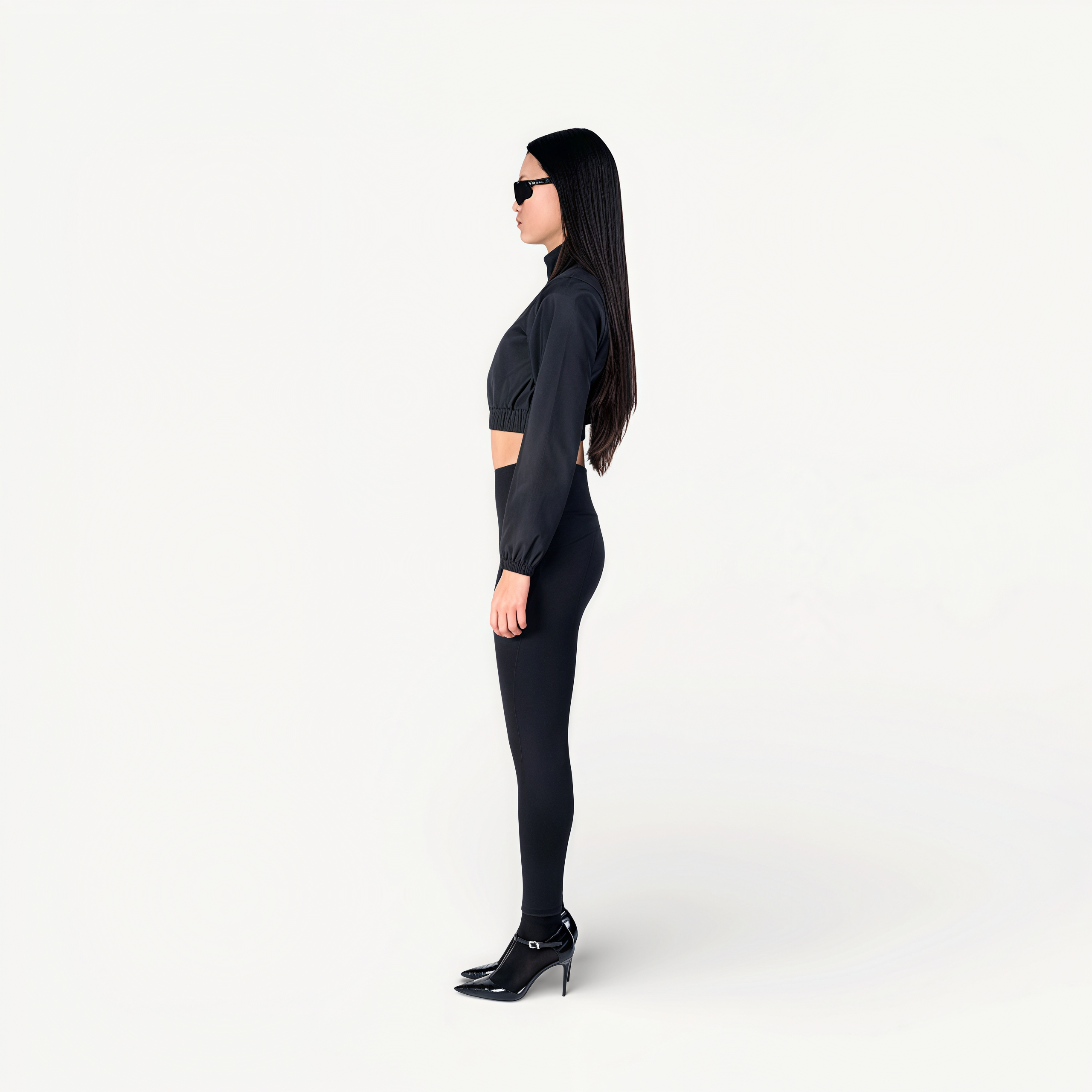 Woman wearing a black athletic outfit on a white background side view.