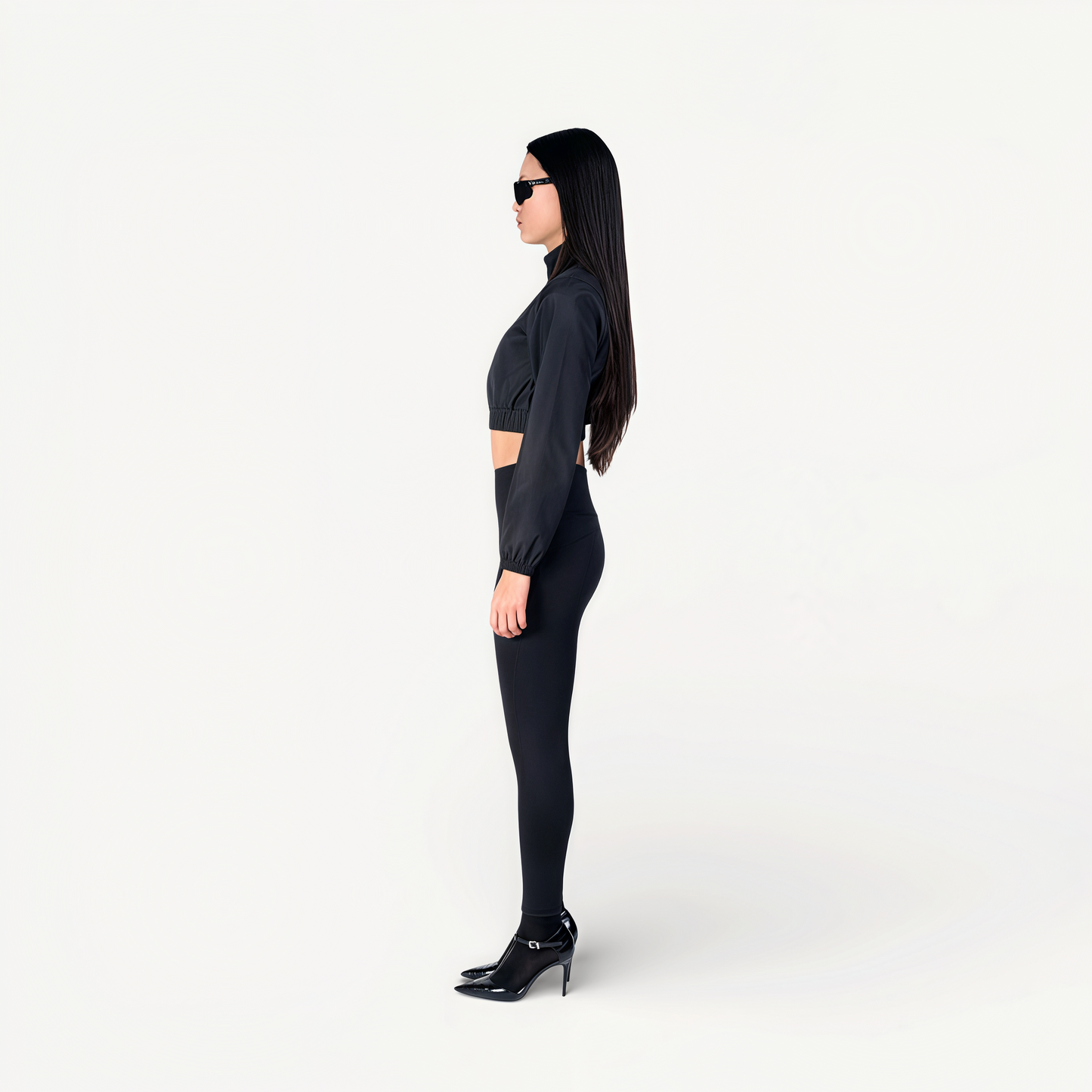 Woman wearing a black athletic outfit on a white background side view.